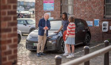 Group of friends chat while their EV is charging in car park